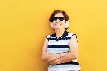 Stylish old woman in sunglasses listening to music with headphones
