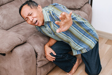 Unhappy elderly senior man suffering from knee ache at home