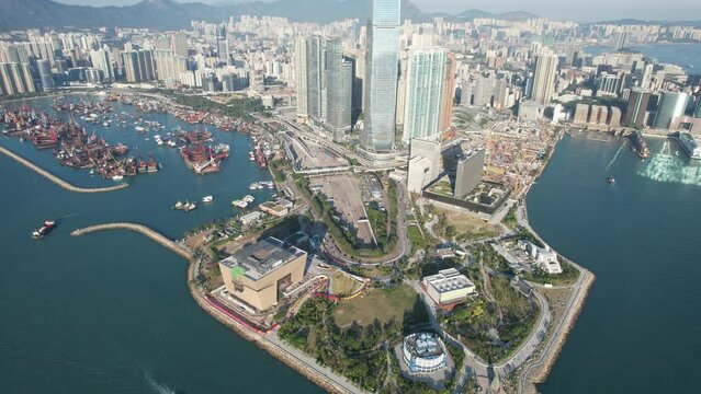 West Kowloon Cultural District, A grass field Waterfront Promenade with the cityscape of high rise buildings near Central, Victoria Harbour, Hong Kong in the background, Aerial view