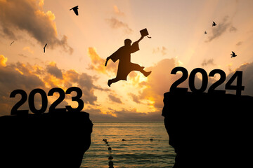 Silhouette Young man Graduation jumping on a cliff in 2024 over a sea cliff at sunset. education congratulation concept, Freedom and Happy New Year, success in the future goal, and passing time. - obrazy, fototapety, plakaty