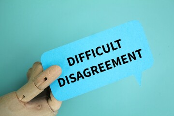 wooden hand holding conversation paper with the word difficult disagreement