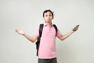 Asian man backpacker hold mobile phone with confused expression. travelling concept. on isolated...