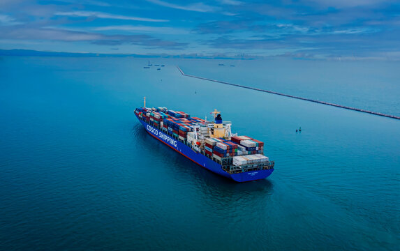 Laem Chabang-Thailand ,  December 19, 2023: The container ship COSCO Shipping arriving to the container terminal. port is fully loaded with cargo containers.