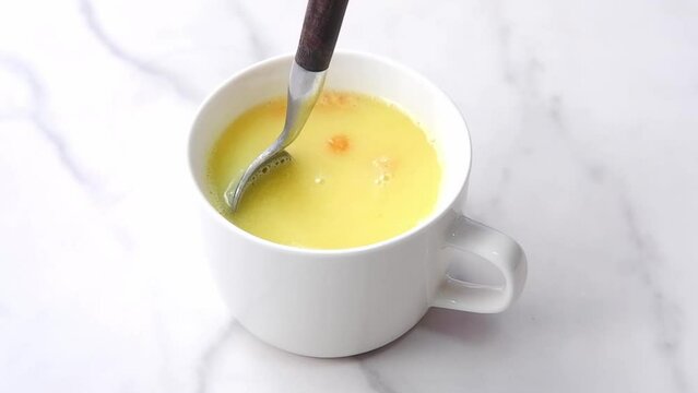 Stirring creamy corn potage with a spoon
