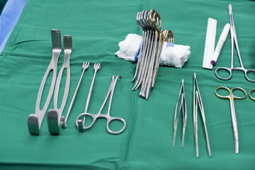 Surgical clamps and medical equipment on green surgical tray inside operating room.Sterile surgical...