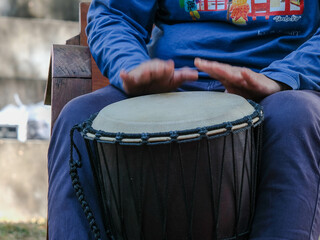 Fototapeta na wymiar Asian man playing rhythmic instrument. A man plays a long drum at a party. Thai musical instruments
