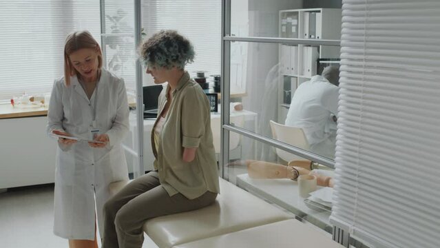 Medical practitioner coming to teenage girl with amputation talking with her about new version of prosthetic