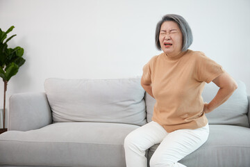 Fototapeta na wymiar senior woman suffering from back pain on sofa