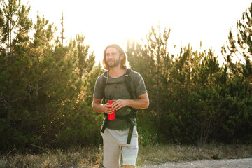Hiker man with backpack holding thermos in his hand