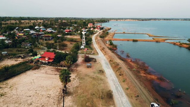 Aerial view of lake flying along the road trough the rural village