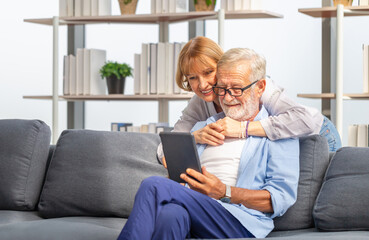 Mature woman and senior man using smartphone talking on video call on cozy sofa at home, Portrait of Cheerful senior couple in living room, Happy family concepts