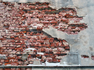 damaged plaster on red brick wall in winter