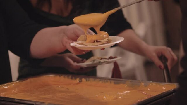 Gooey Hot Steamy Cheese Being Scooped Onto Plate Of Nacho Chips At Buffet