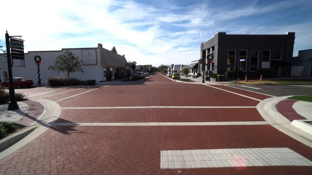 Wide angle dolly establishes historic red brick road of Downtown Clermont Florida at midday
