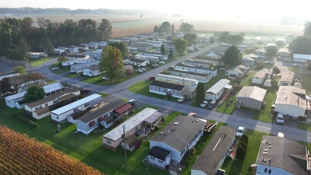 Rural mobile home trailer park during sunrise. Aerial shot of manufactured houses with corn fields in American countryside.