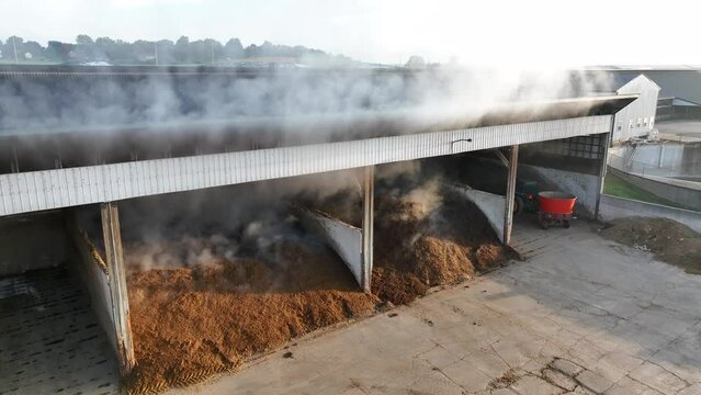 Steam rising from composting manure at a farm storage facility. Aerial shot during cold morning sunrise.