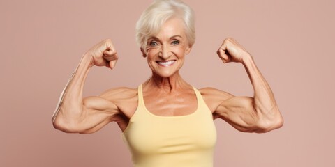 An older woman flexing her muscles in a yellow tank top. Suitable for fitness and healthy lifestyle concepts - obrazy, fototapety, plakaty