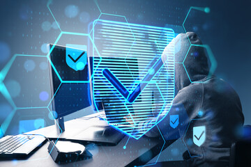 Side view of hacker at desktop using laptop with glowing hexagonal shield hologram with binary coding on blurry background. Safety, hacking, malware and internet concept. Double exposure.