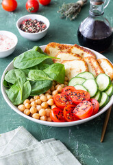 Bowl with grilled Halloumi cheese, spinach, chickpeas, tomatoes and cucumbers. Healthy eating. Vegetarian food. Diet.