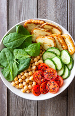 Bowl with grilled Halloumi cheese, spinach, chickpeas, tomatoes and cucumbers. Healthy eating. Vegetarian food. Diet.