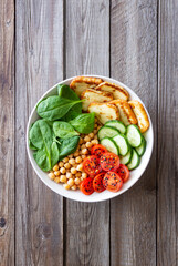 Bowl with grilled Halloumi cheese, spinach, chickpeas, tomatoes and cucumbers. Healthy eating. Vegetarian food. Diet.