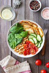 Bowl with grilled Halloumi cheese, spinach, chickpeas, tomatoes and cucumbers. Healthy eating. Vegetarian food. Diet.