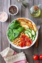 Bowl with grilled Halloumi cheese, spinach, chickpeas, tomatoes and cucumbers. Healthy eating. Vegetarian food. Diet.