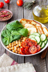 Bowl with grilled Halloumi cheese, spinach, chickpeas, tomatoes and cucumbers. Healthy eating. Vegetarian food. Diet.