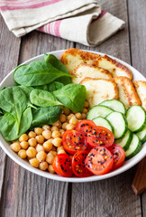 Bowl with grilled Halloumi cheese, spinach, chickpeas, tomatoes and cucumbers. Healthy eating. Vegetarian food. Diet.