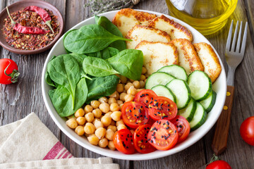 Bowl with grilled Halloumi cheese, spinach, chickpeas, tomatoes and cucumbers. Healthy eating. Vegetarian food. Diet.