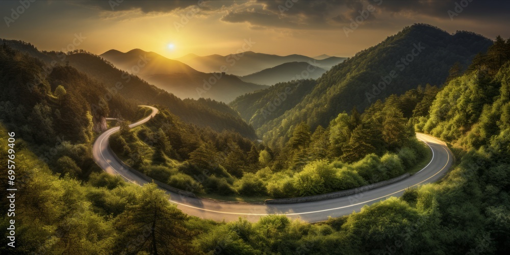 Wall mural a winding road through a forested mountain area at sunset. - Wall murals