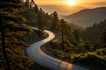 A winding road through a forested mountain area at sunset.