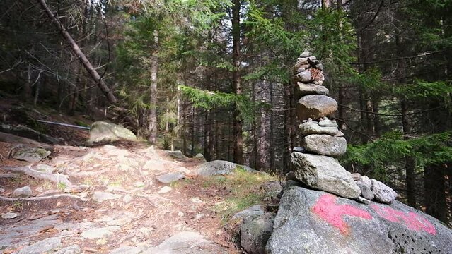 Stacked stones in the Bagni di Masino forest, arrow on a rock to indicate the direction along the path to the Onio refuge in the Oro Valley, Val Masino.
