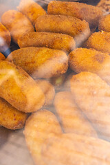 Crocchè di patate fritti tradizionali napoletani fatti a mano e esposti in una vetrina da vendita...