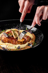 woman hands with fork and knife eating beef steak in cafe