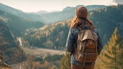 Foto op Canvas candid shot from the back of a young woman traveler in vintage style with a tourist backpack looking at the stunning view of the mountains and forest. travel and hiking concept. copy space. © ALL YOU NEED studio