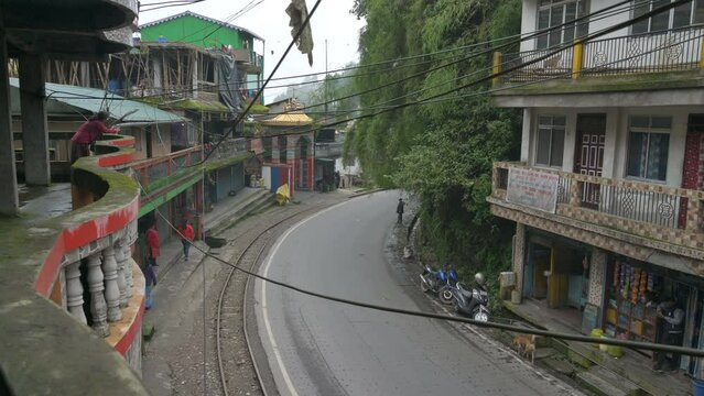 Darjeeling,West Bengal,India - 21.08.2023 : Steam engine Toy train passing through Himalayan road of Ghum city. Historical famous Unesco world heritage of Darjeeling Himalayan Railway, narrow gauge.