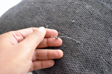 Snagged thread from cat scratches on a cushion cover. Selective focus. Copy space. 