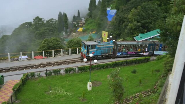 Darjeeling,West Bengal,India- 20.08.2023 : Famous Diesel Toy train passing through Batasia loop, memorial to the Gorkha soldiers of the Indian Army. Darjeeling Himalayan Railway, narrow gauge railway.