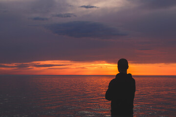 Silhouette of a man looking at the sunset on the embankment of the Black Sea coast in Kobuleti, loading.