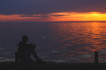 Silhouette of a man looking at the sunset on the embankment of the Black Sea coast in Kobuleti, loading.