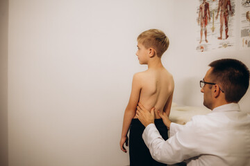 Orthopedist examining child's back in clinic. Scoliosis treatment - Powered by Adobe