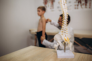 A pediatric neurologist doctor examines the back of a 5-year-old boy who has back pain. Treatment...