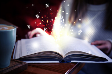 Woman reading shiny magic book with letters flying over it, closeup