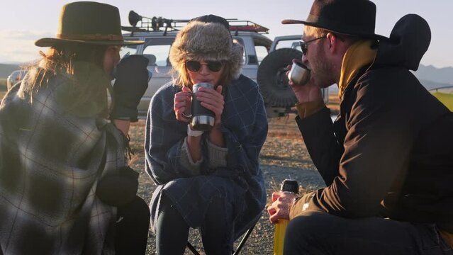 Group of Friends reparing coffee near travel suv. People enjoying a day camping. Autumn vacations and relationship concept. Picnic near car on sunset outside. Domestic travel concept.