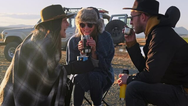 Group of Friends reparing coffee near travel suv. People enjoying a day camping. Autumn vacations and relationship concept. Picnic near car on sunset outside. Domestic travel concept.