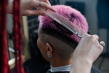 Asian woman with pink hair getting a haircut in a barbershop. 