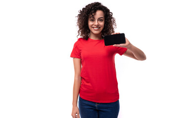 young active curly brunette woman dressed in a casual basic red t-shirt showing the screen of a mobile phone
