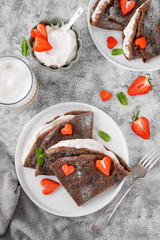 Chocolate crepes or pancakes with cream cheese filling and fresh strawberries in the shape of...
