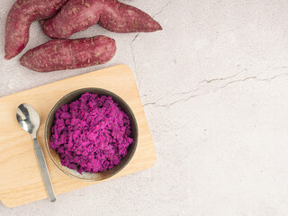Purple yams pile and mashed purple sweet potatoes on a bowl on a cutting wooden board